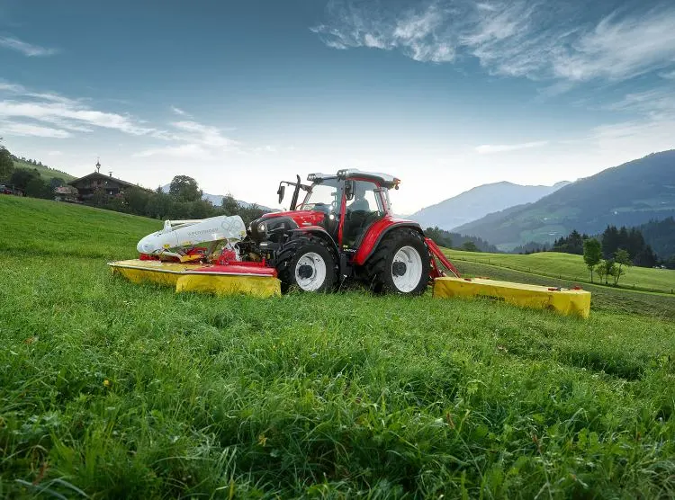 Auf einem saftigen, grünen Feld parkt ein Traktor, der die ländliche Idylle unterstreicht.
